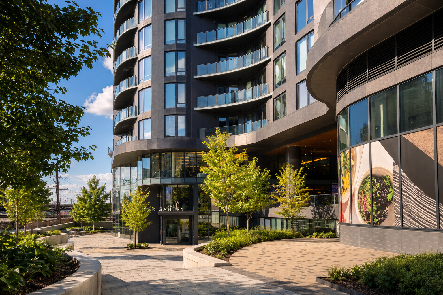 Landscaped entrance courtyard beneath curved balconies at The Gantry apartment building.