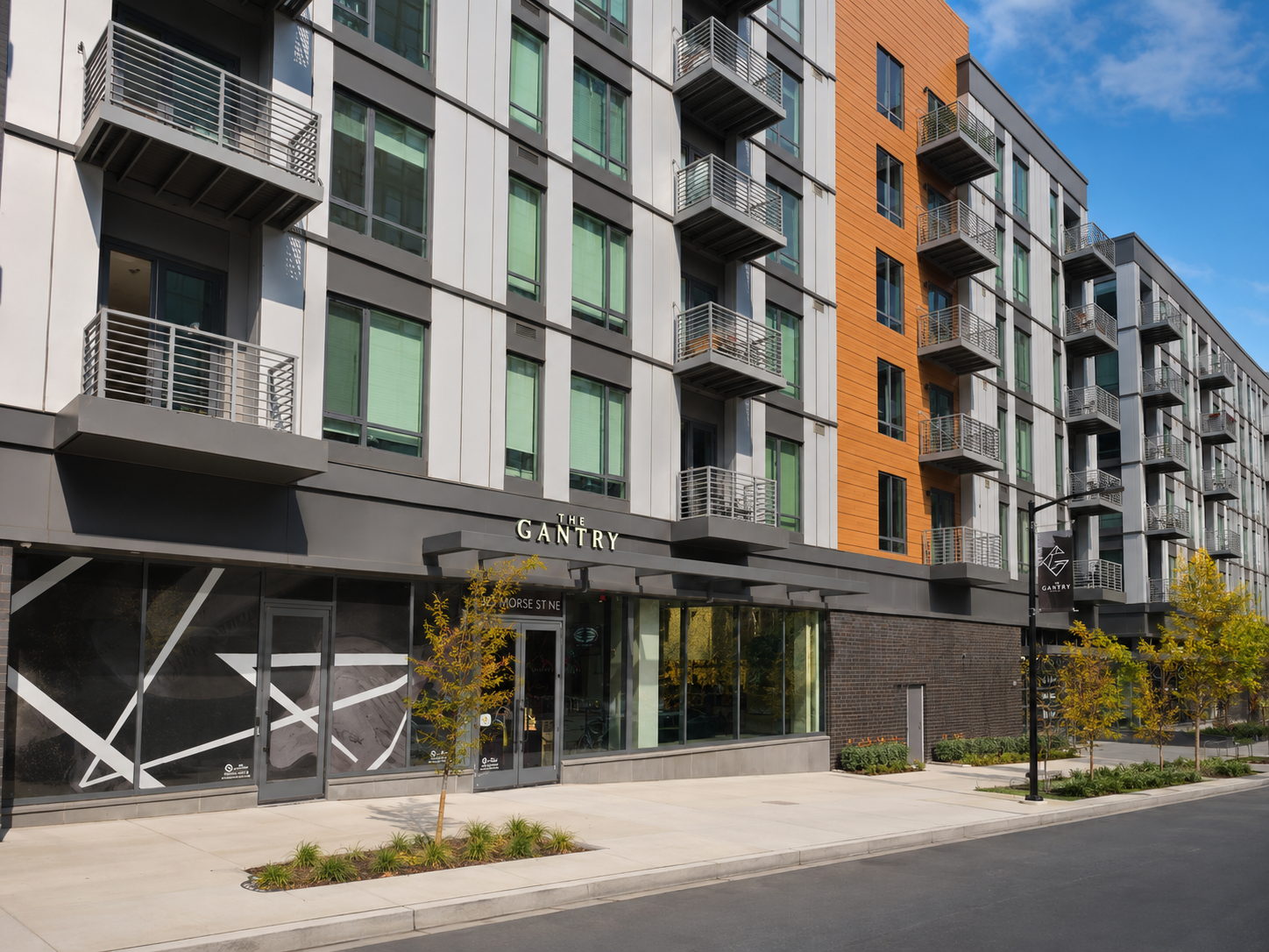 Street-level entrance to The Gantry apartments, featuring gray panels, wood accents, and metal balconies.